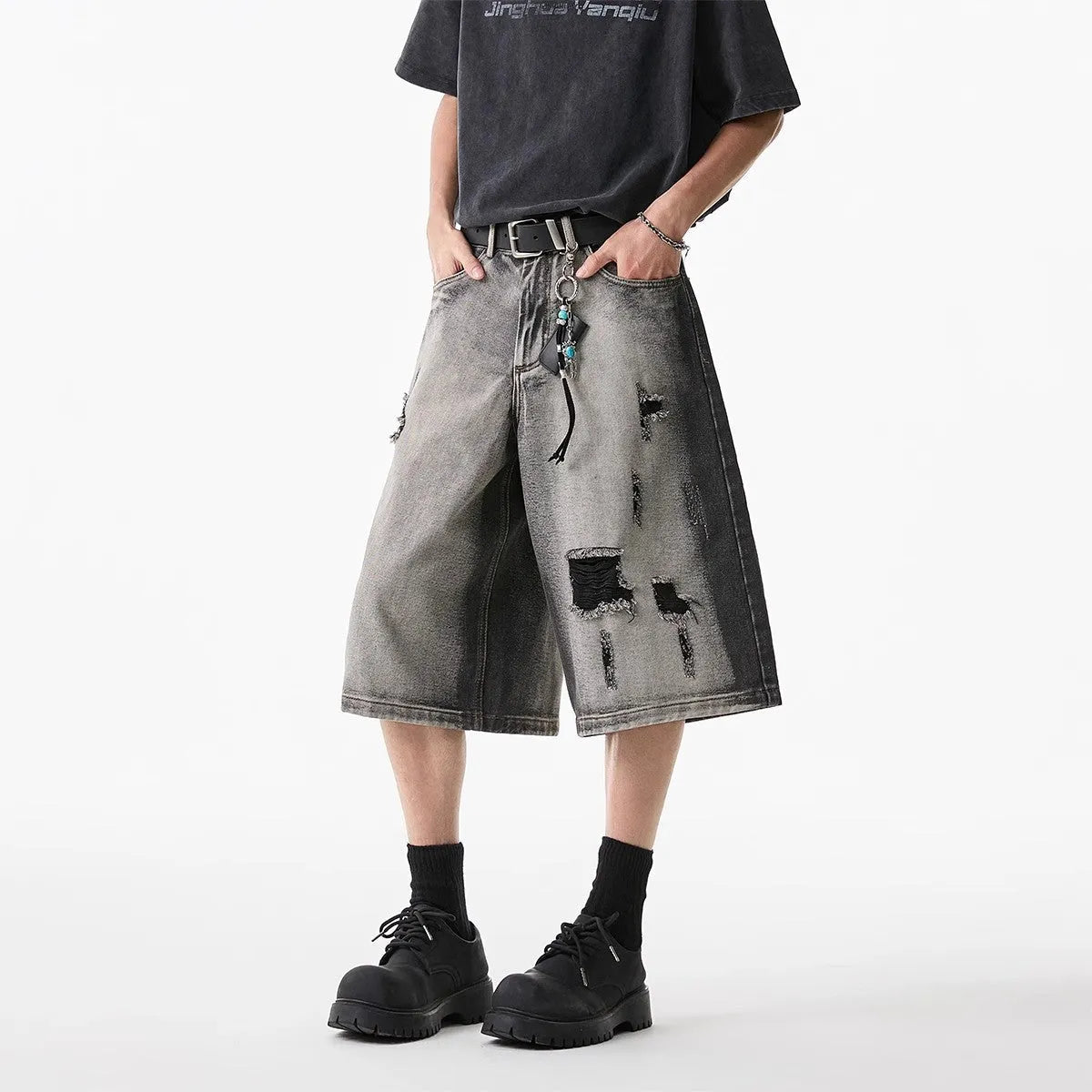Gray distressed denim shorts with hole detailing, loose cropped fit on a plain background.