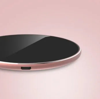 Ultra-thin aluminum wireless charger in silver on a desk next to a phone.