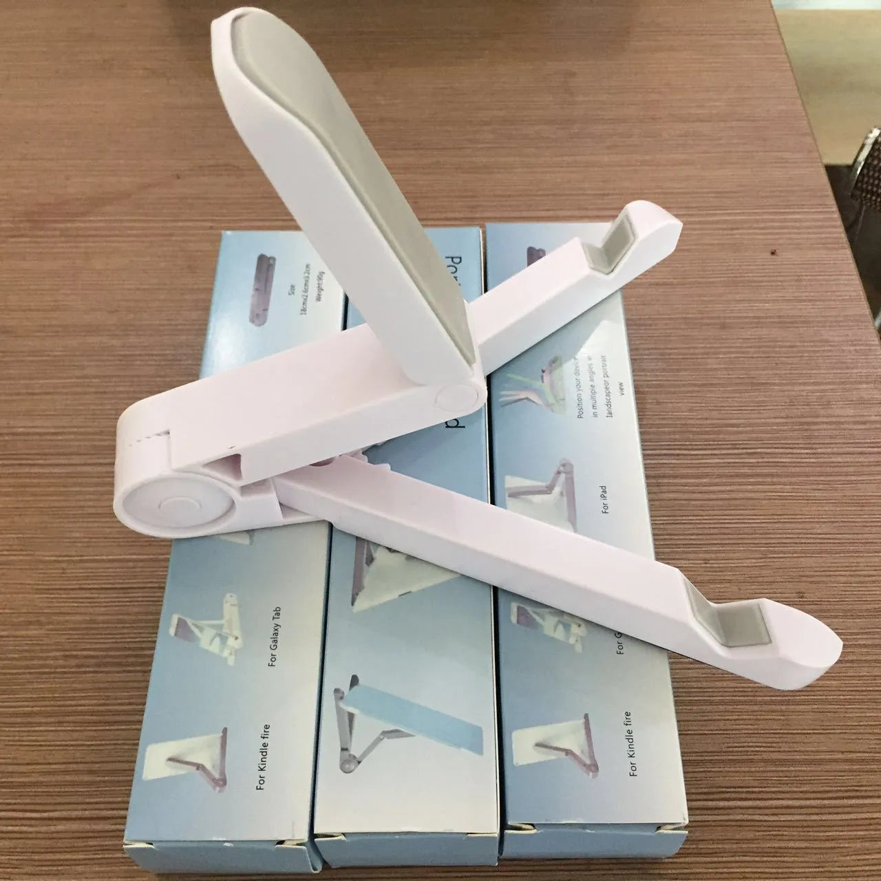 Black foldable tablet holder standing upright with a tablet device resting on its non-slip rubber surface.