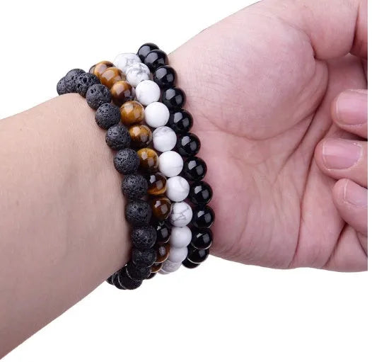 Close-up of a women's geometric bracelet with black agate beads on a black elastic cord.