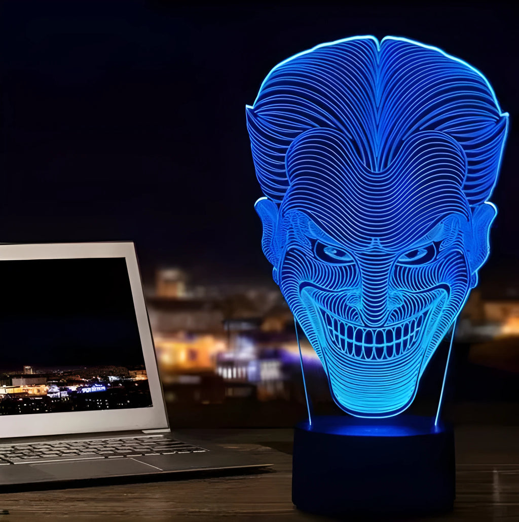 A 3D acrylic LED lamp showing a gradient of colours, sitting on its square base with a remote control nearby.