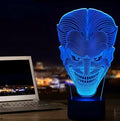 A 3D acrylic LED lamp showing a gradient of colours, sitting on its square base with a remote control nearby.