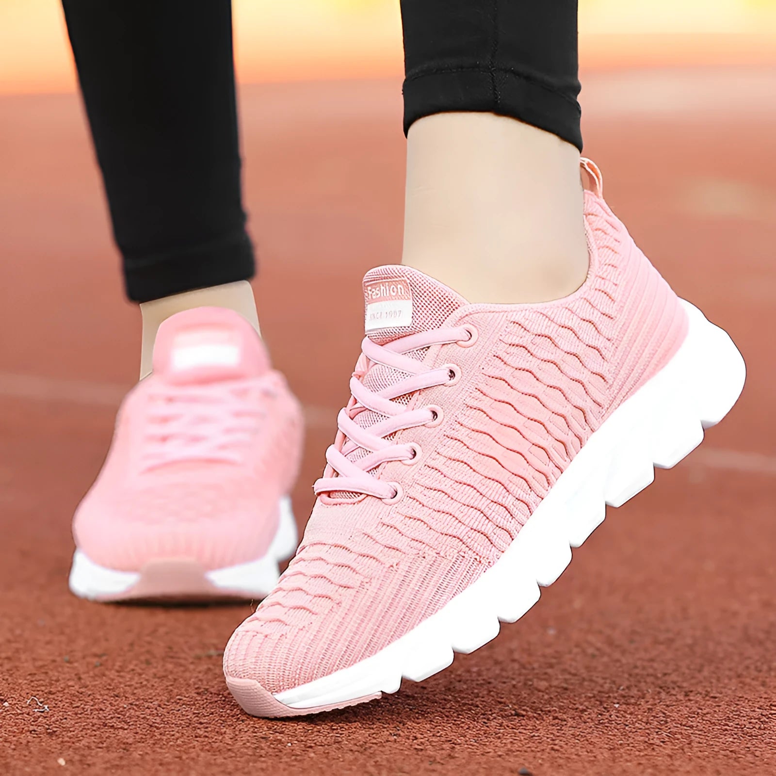 Women's running shoes in black, pink, or white with a woven fly knit upper and textured outsole.