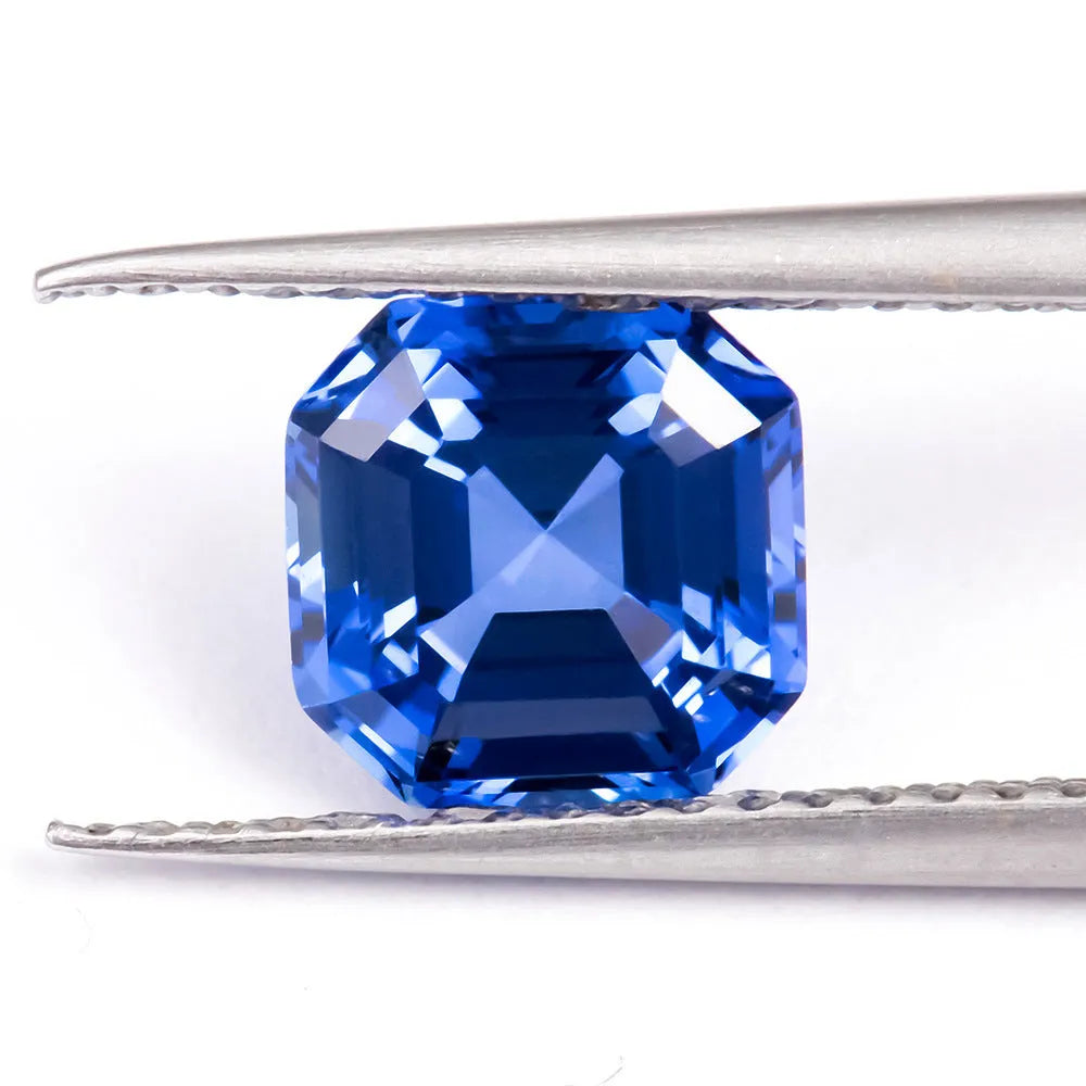 Royal blue loose cultured gemstone in heart, round, and pear shapes on a grey background.