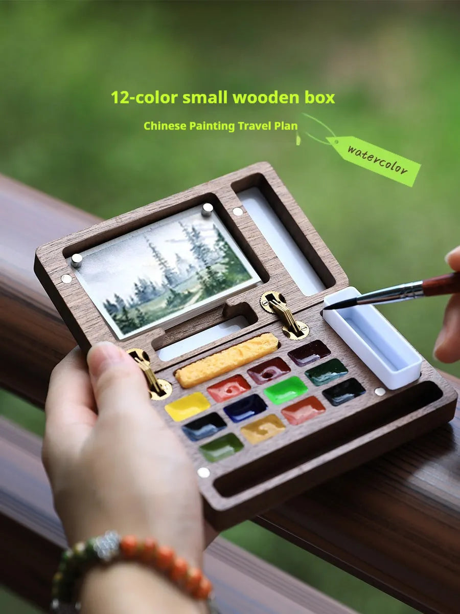 Mini walnut wood watercolour paint box open to show pigment pans with leather carrying bag