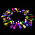 Solar-powered LED outdoor string lights with bubble drop pendants decorating a garden fence