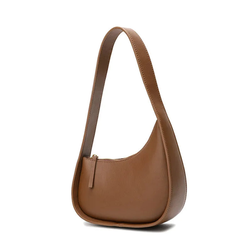 Women's half moon shaped leather shoulder bag in light brown with an adjustable wide strap.