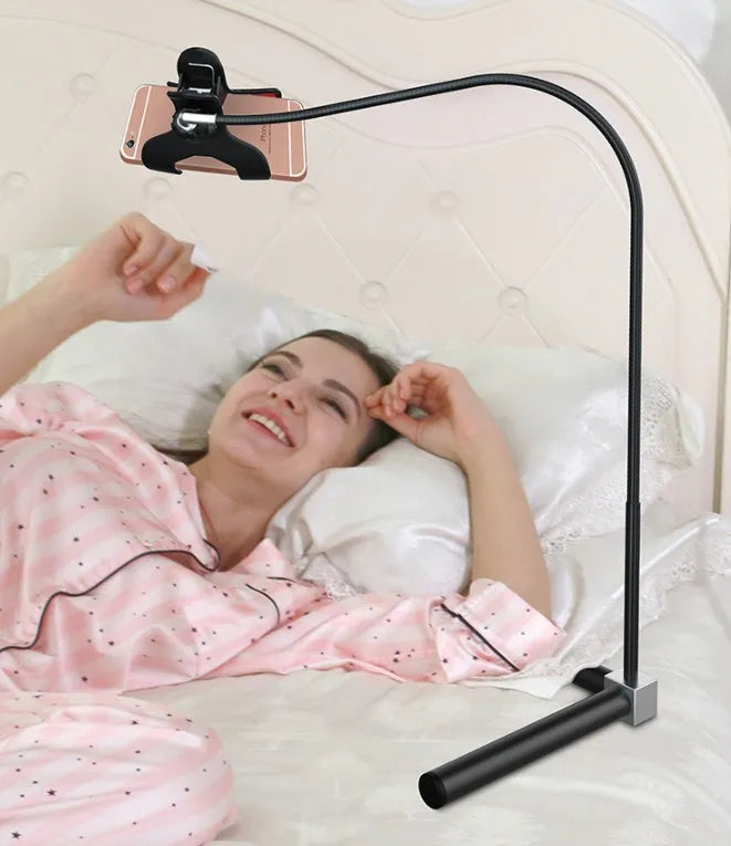 Black mobile phone bed bracket mounted on bedside with phone secured in universal folder for hands-free viewing