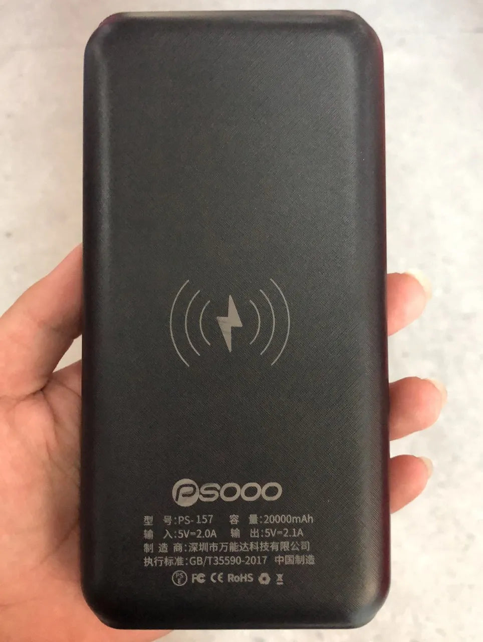 Black portable power bank with solar panel, wireless charging surface, and three USB output ports