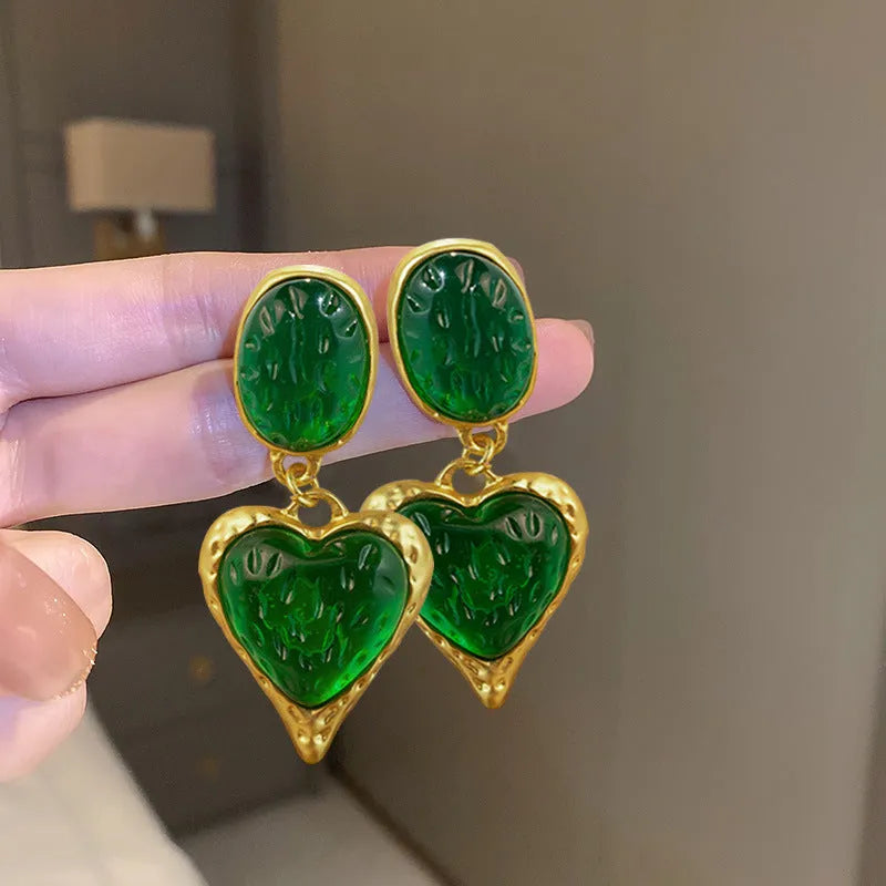 A pair of oval-shaped, pleated love heart stud earrings in alloy, shown in various colours.