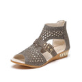 Women's beige flat sandals with wedge heel, rivet detail, and back zipper.