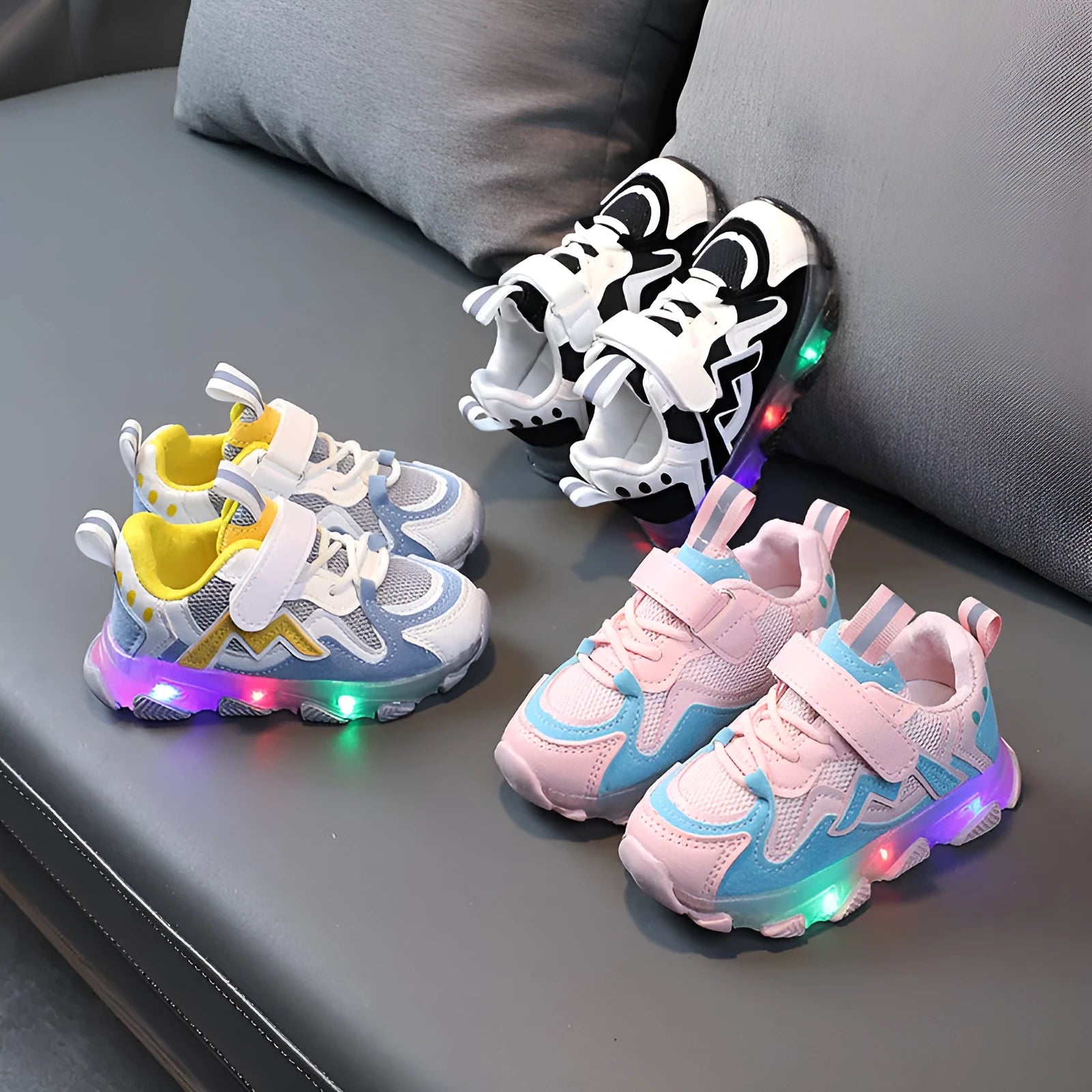 Children's bright light sports sneakers with mesh panels and Velcro strap in black, grey, or pink.