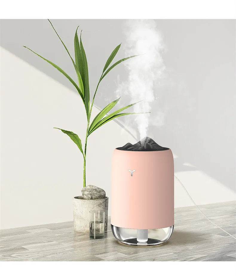 White Magic Flame columnar ultrasonic humidifier with USB cable on a wooden desk.