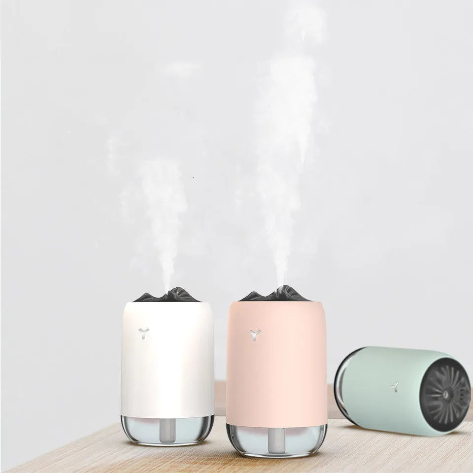 White Magic Flame columnar ultrasonic humidifier with USB cable on a wooden desk.