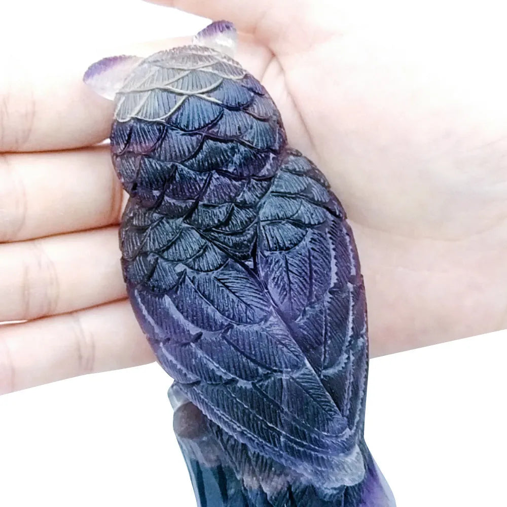 Hand-carved purple fluorite owl ornament on neutral background showing natural stone colouration