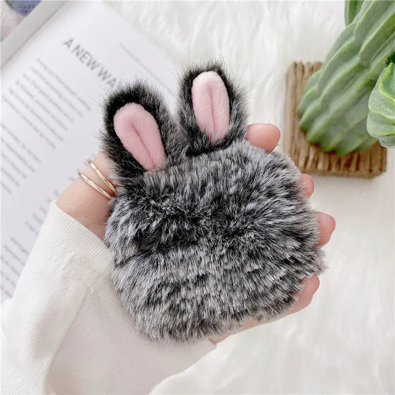Pink silicone AirPods case cover with raised rabbit ears on a table.