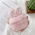 Pink silicone AirPods case cover with raised rabbit ears on a table.
