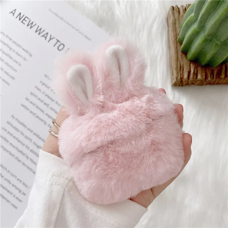 Pink silicone AirPods case cover with raised rabbit ears on a table.