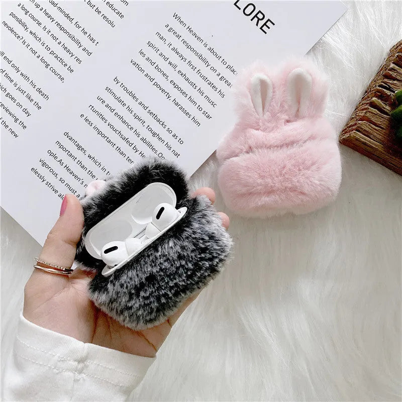 Pink silicone AirPods case cover with raised rabbit ears on a table.