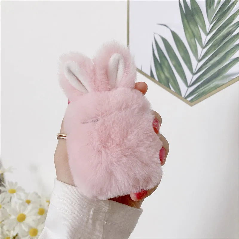 Pink silicone AirPods case cover with raised rabbit ears on a table.