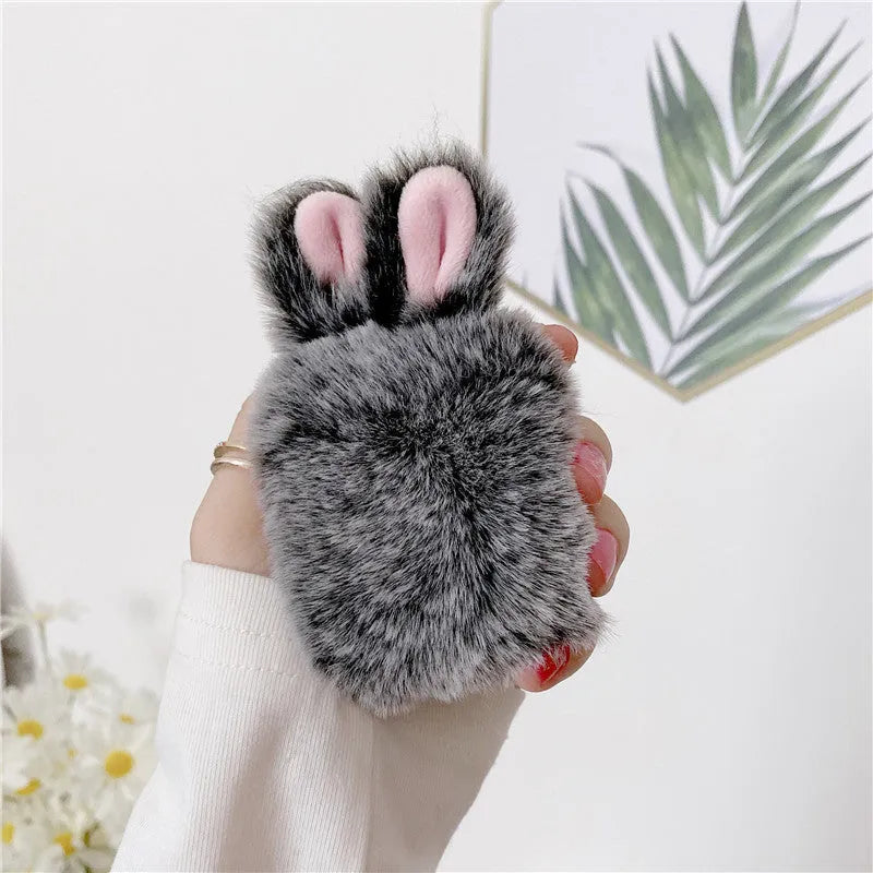 Pink silicone AirPods case cover with raised rabbit ears on a table.