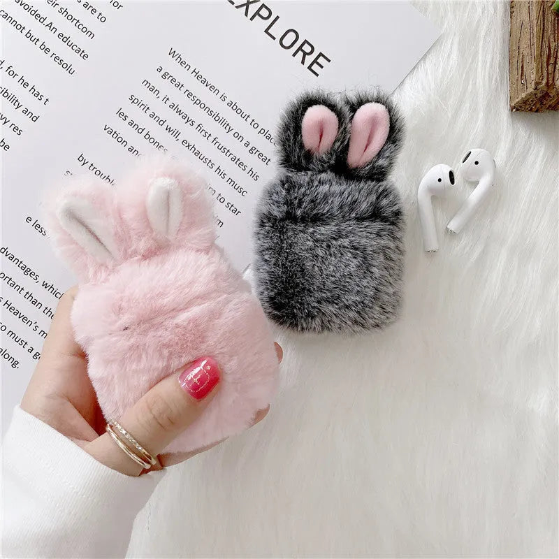 Pink silicone AirPods case cover with raised rabbit ears on a table.