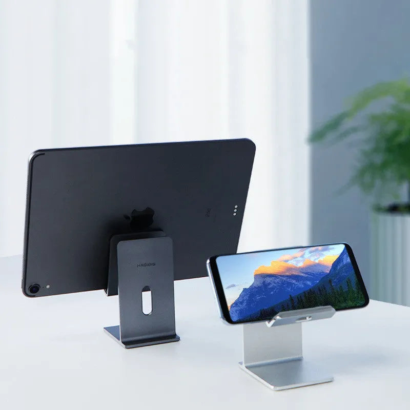 Alloy mobile phone holder with adjustable bracket in dark grey or silver colour on desktop