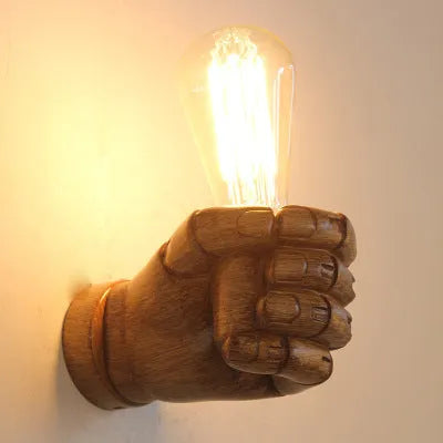 Creative fist-shaped resin wall lamp in black, mounted on a wall, for corridor or restaurant decoration.