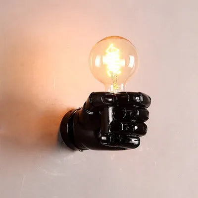 Creative fist-shaped resin wall lamp in black, mounted on a wall, for corridor or restaurant decoration.