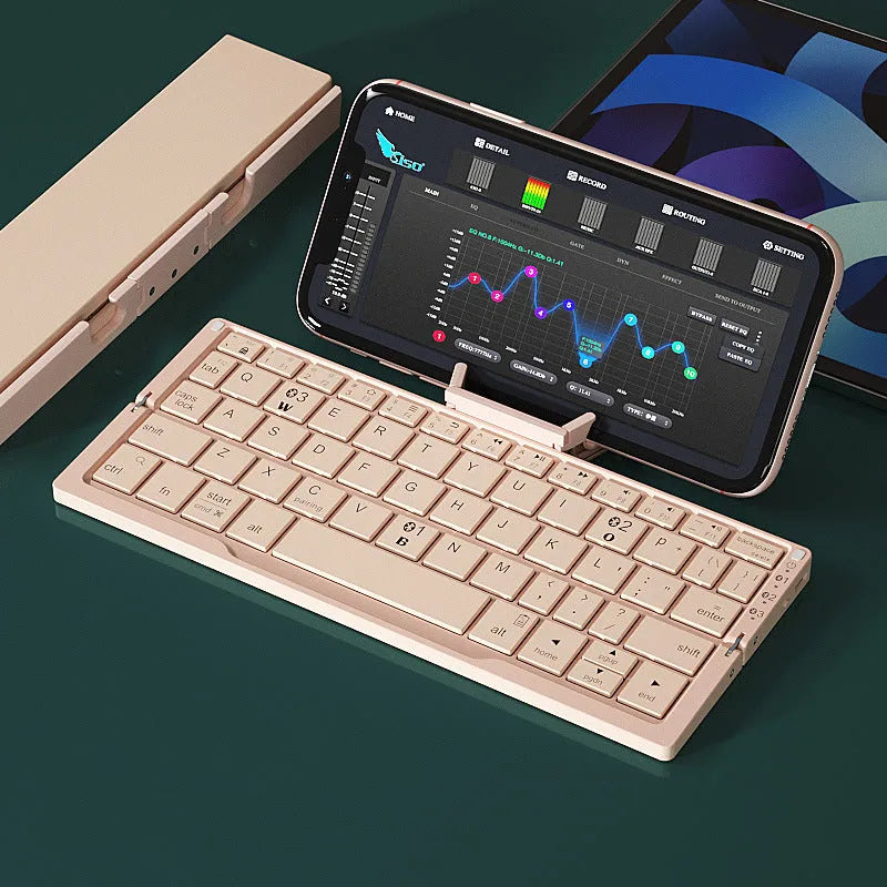 Silver white folding Bluetooth keyboard open next to a smartphone on its built-in metal stand.