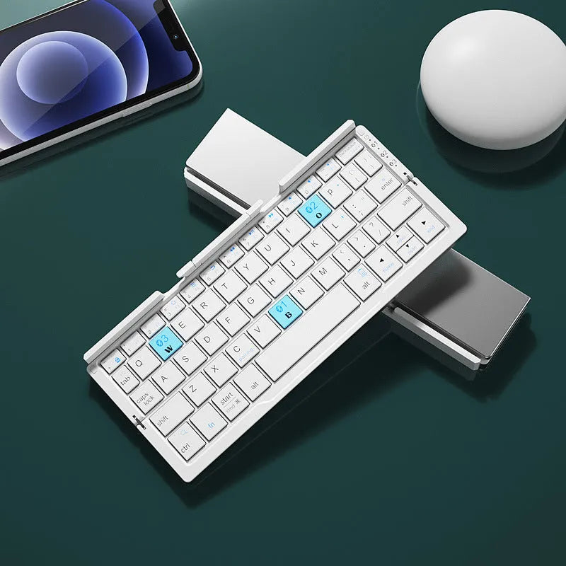 Silver white folding Bluetooth keyboard open next to a smartphone on its built-in metal stand.