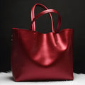 Women's structured cowhide shoulder bag in black with an adjustable strap.