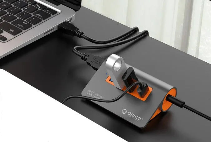 Dark grey aluminium USB-C hub with four USB 3.1 ports and orange accents beside detached 100cm cable