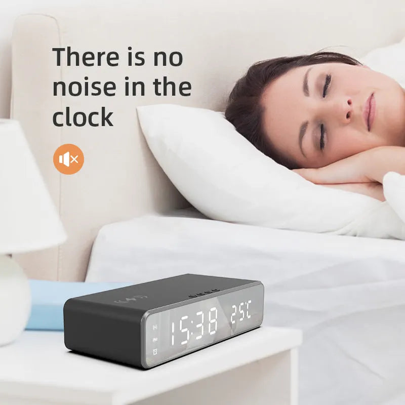Silver wireless phone charger with clock display, thermometer reading, and integrated mirror on a desk