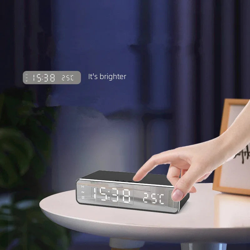 Silver wireless phone charger with clock display, thermometer reading, and integrated mirror on a desk
