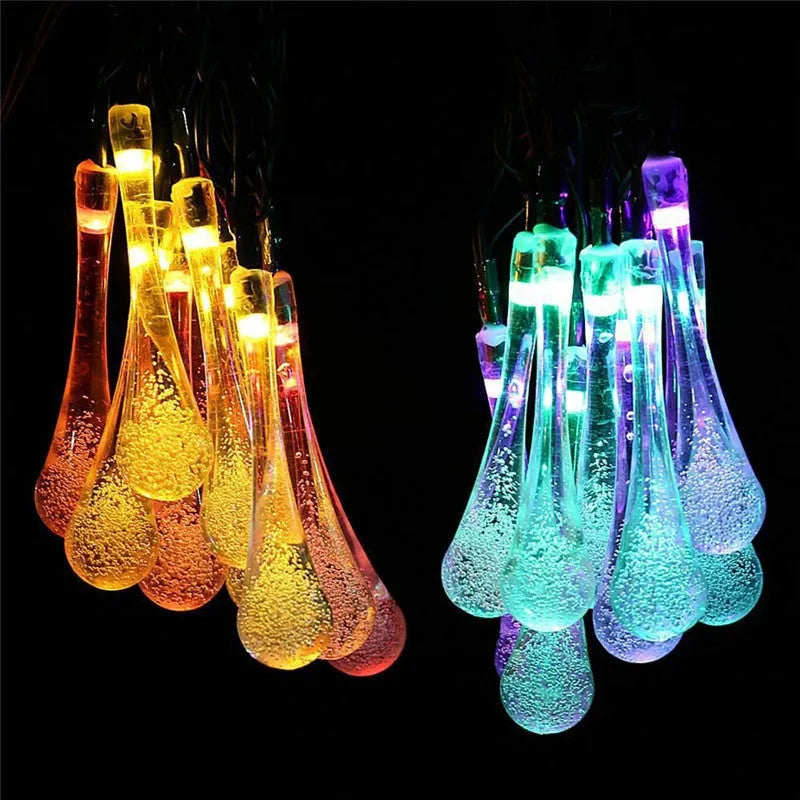 Solar-powered LED outdoor string lights with bubble drop pendants decorating a garden fence
