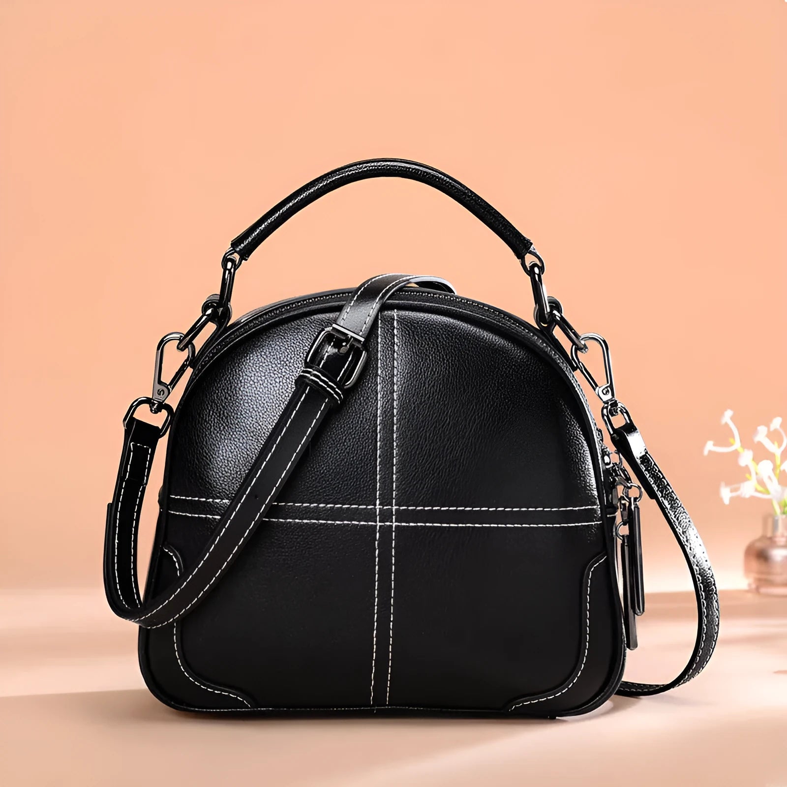 Round leather handbag with soft handles and zipper closure in wine red colour