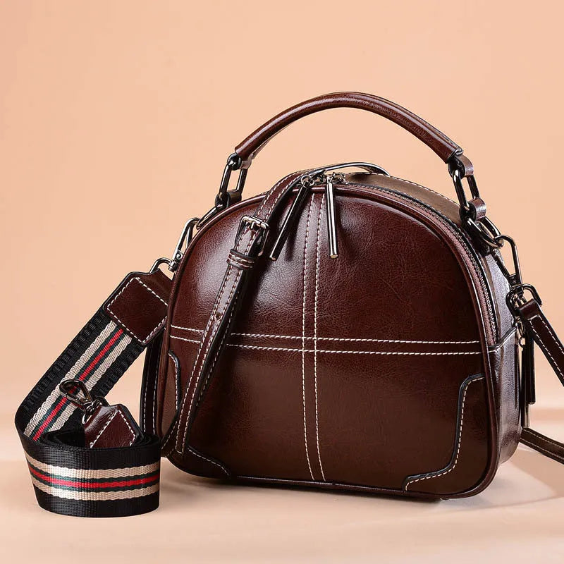 Round leather handbag with soft handles and zipper closure in wine red colour