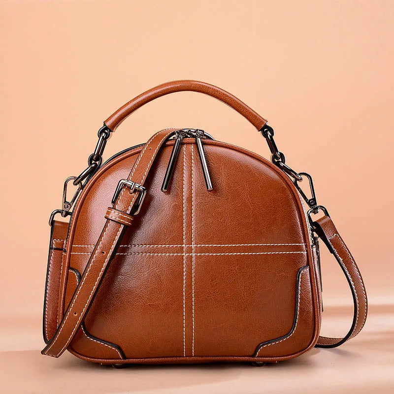Round leather handbag with soft handles and zipper closure in wine red colour