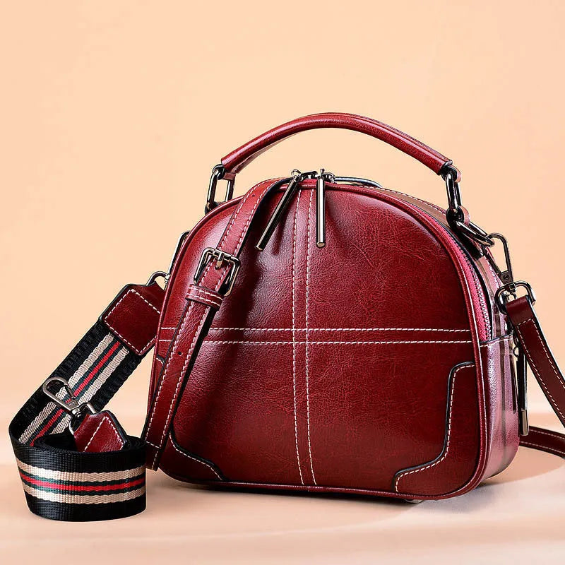 Round leather handbag with soft handles and zipper closure in wine red colour