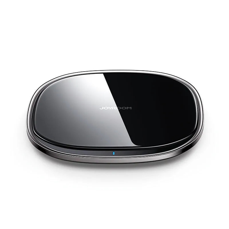 Black 15W wireless fast charger with zinc alloy frame and glass top on a wooden desk.
