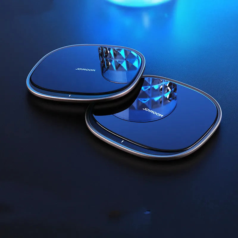 Black 15W wireless fast charger with zinc alloy frame and glass top on a wooden desk.