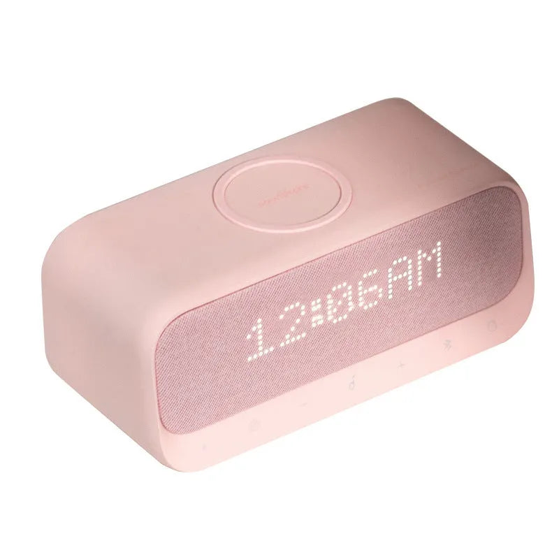 Compact pink and white Soundcore Bluetooth speaker with wireless charging pad and digital alarm clock display.