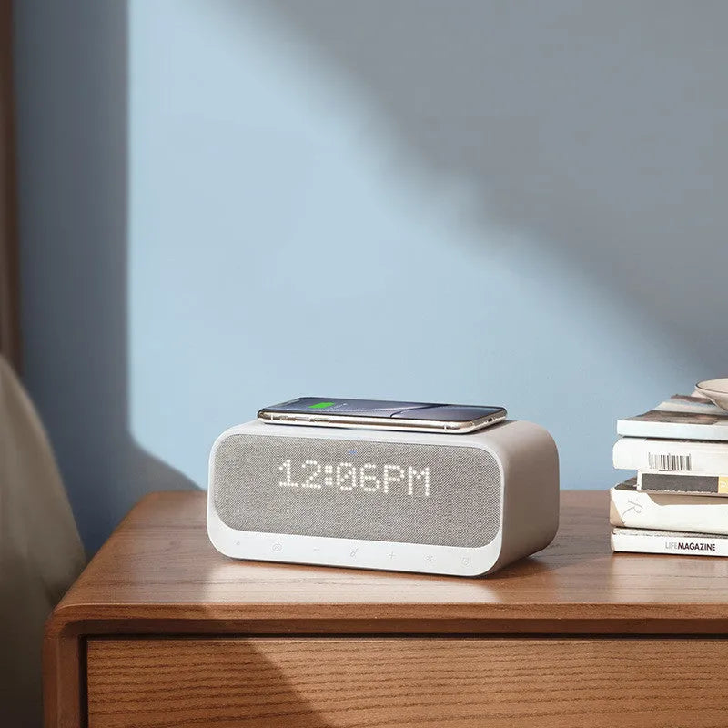 Compact pink and white Soundcore Bluetooth speaker with wireless charging pad and digital alarm clock display.