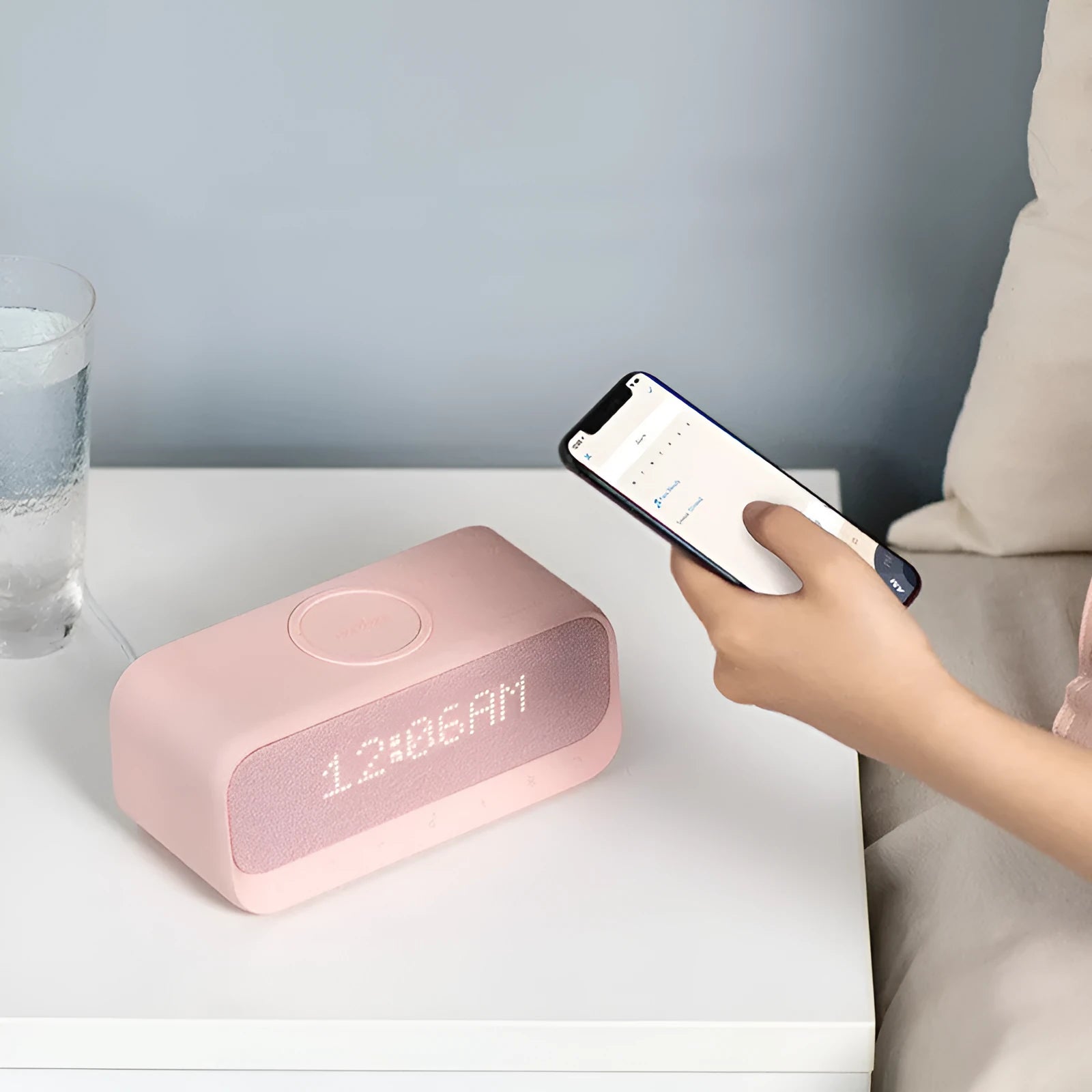 Compact pink and white Soundcore Bluetooth speaker with wireless charging pad and digital alarm clock display.