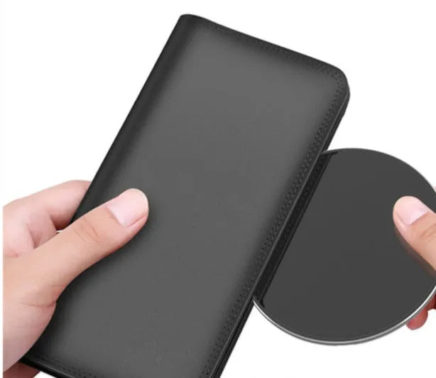 Ultra-thin aluminum wireless charger in silver on a desk next to a phone.