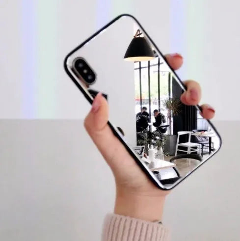 Black mirror iPhone back cover case for iPhone 7 Plus, 8 Plus, and X models on a table.