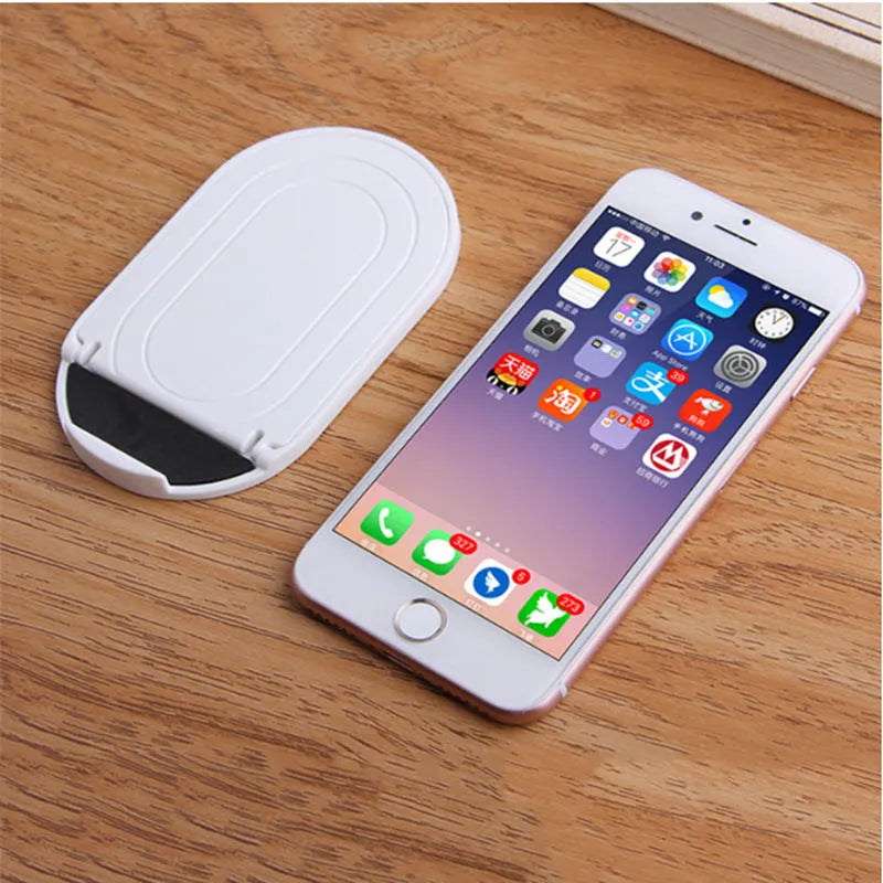 Plastic mobile phone stand with adjustable lazy bracket in six colour options on tabletop