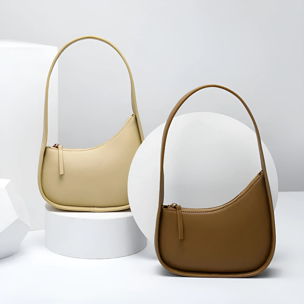 Women's half moon shaped leather shoulder bag in light brown with an adjustable wide strap.