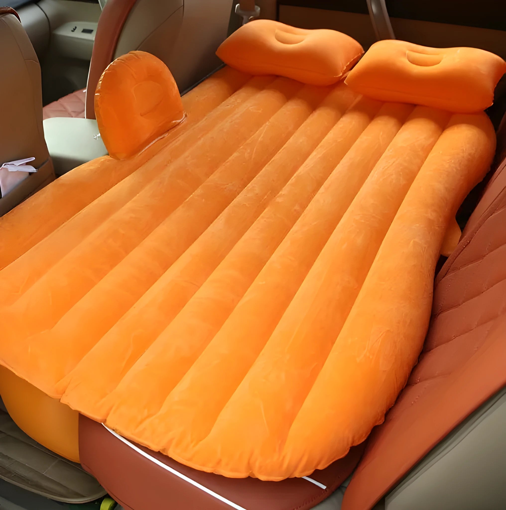Black inflatable car bed with flocked material and two pillows, set up in a car's rear seats.